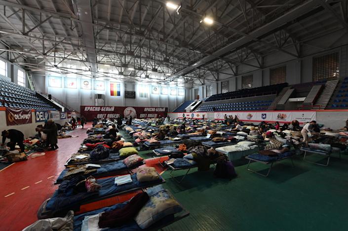 Evacuees sort out their belongings in a local sports school arrayed with dozens of temporary beds.
