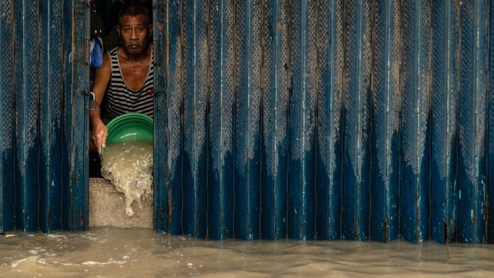 A villager scoops out the floodwater brought by Tropical Storm Nalgae inside his property in Bacoor, Cavite, Philippines