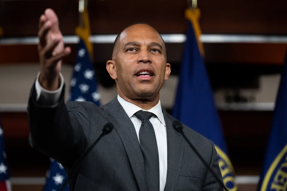 Representative Hakeem Jeffries stands at a podium during a news conference.